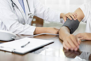 A provider putting a blood pressure cuff on an employee's arm