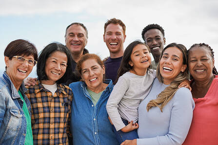 A smiling group of 8 people of many ages